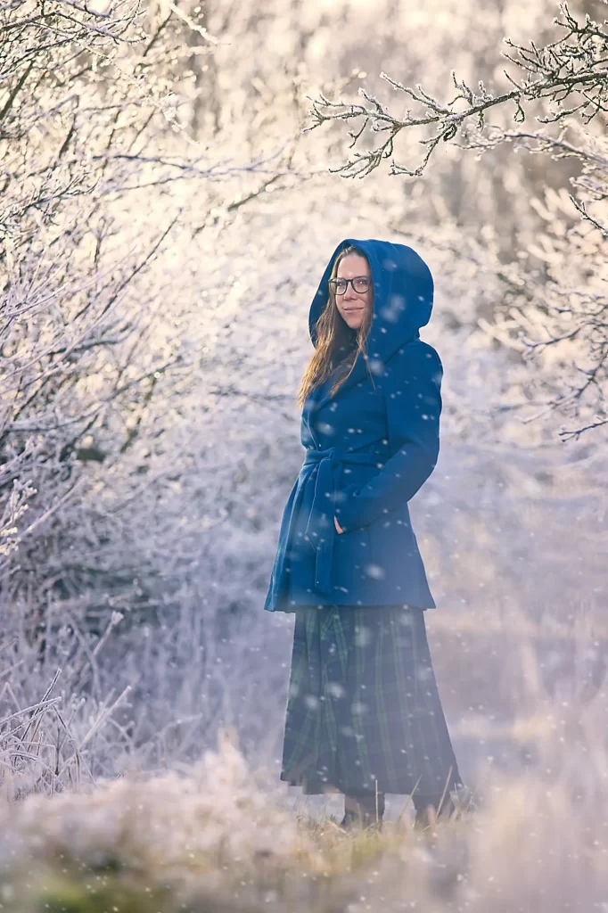 a woman standing in a snowy forest