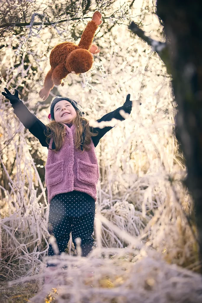 a girl throwing a teddy bear in the air